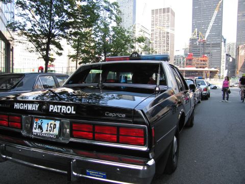 1991 Ford LTD Crown Victoria - Rear view of a black Chevrolet Caprice Highway Patrol sedan showing a Wyoming license plate and roof light bar, parked near a city construc…