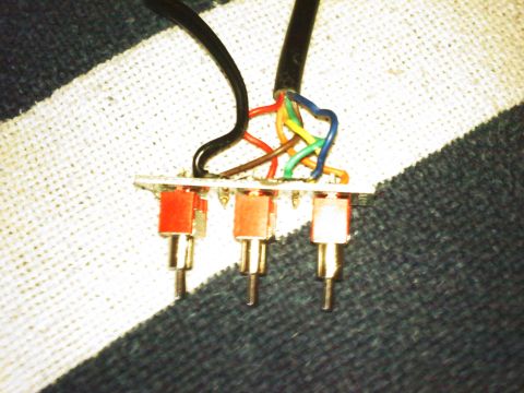 1996 Ford Bronco - This image shows a close-up of a wiring harness with four red switches and multiple colored wires connected.