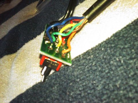 1996 Ford Bronco - A close-up view of a circuit board with various wires attached to a switch, resting on a textured surface.