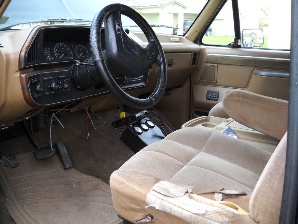 Tan interior of a 1987 Ford F-Series truck showing the dashboard, steering wheel, and passenger seat