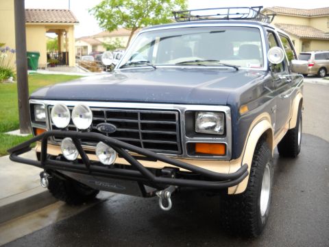 1986 Ford Bronco - Front view of a blue Ford Bronco with a custom bumper and auxiliary lights.