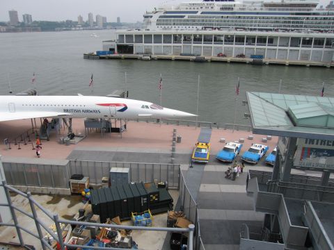 1991 Ford LTD Crown Victoria - British Airways Concorde on a waterfront display platform with police vans parked nearby and a large cruise ship across the water.