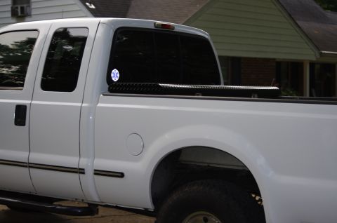 1999 Ford F-250 - White pickup truck with a toolbox and an emblem on the rear window.