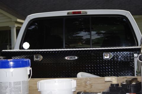 1999 Ford F-250 - The rear of a 1999 Ford F-250 pickup truck is shown, equipped with a black toolbox and white buckets in the bed.
