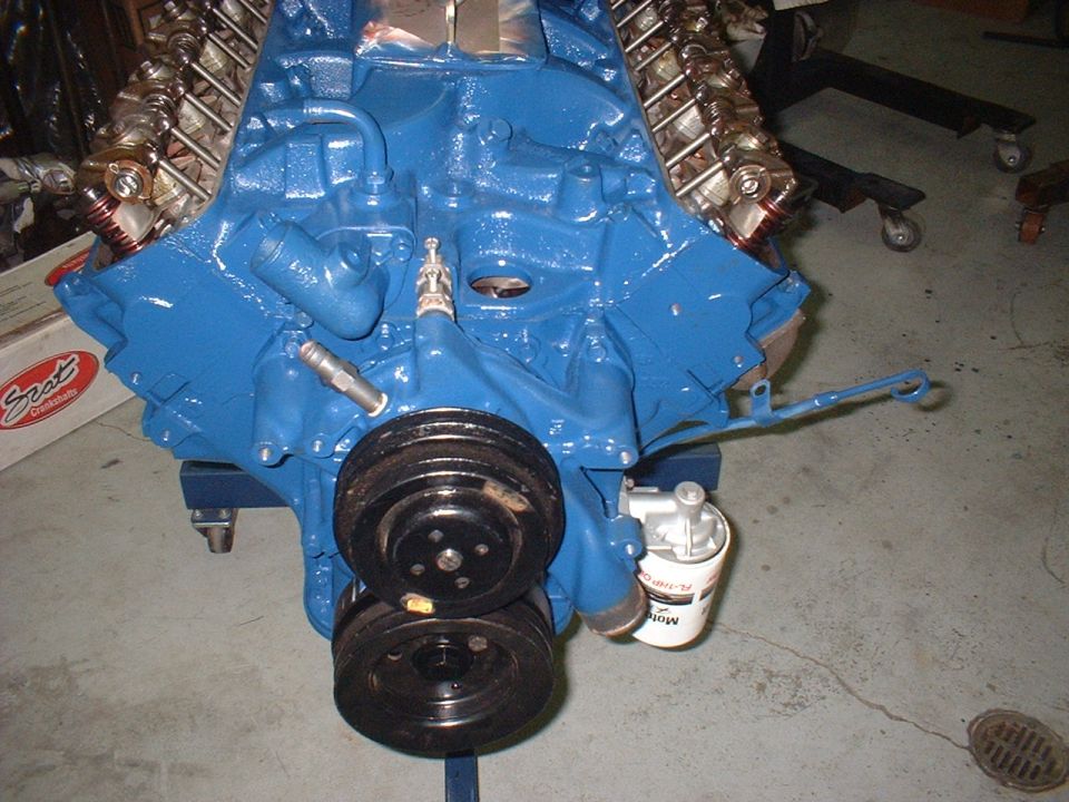 Blue engine block with dual pulleys and oil filter. Text on oil filter is partially visible