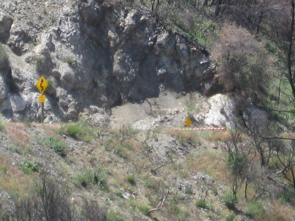 Winding mountain road with yellow warning signs for curves and caution tape