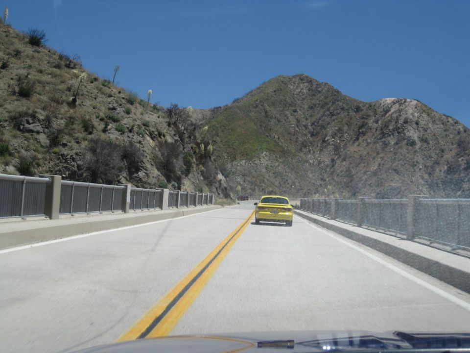Yellow car driving on a highway with mountains in the background