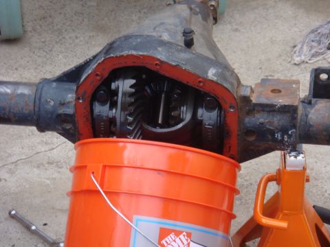 1992 Ford Bronco - Differential housing with gears visible, supported by a jack stand and with an orange bucket catching fluid.