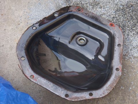 1992 Ford Bronco - Differential cover with oil, resting on concrete.