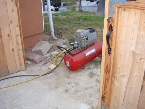 1992 Ford Bronco - Air compressor and hoses are visible next to a wooden gate and building exterior.
