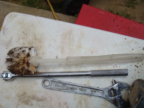 1992 Ford Bronco - Tools and a dirty toilet brush are laid out on a white surface, possibly for cleaning or repair.