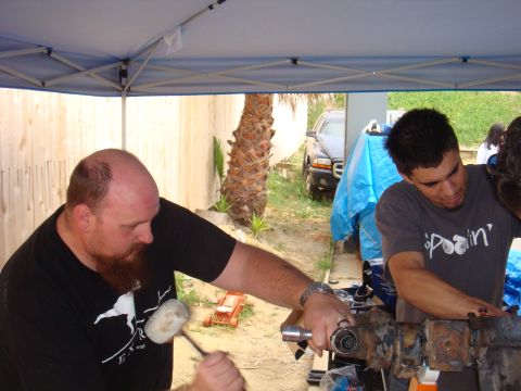 1992 Ford Bronco - Men assemble a vehicle part outdoors, with a dark SUV in the background.