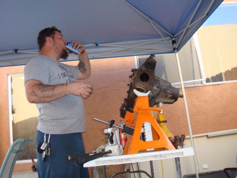 1992 Ford Bronco - A man drinks from a can next to a front axle assembly supported by jack stands.