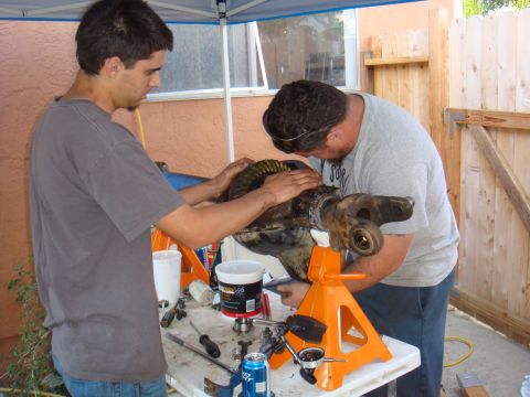 1992 Ford Bronco - Men working on a vehicle axle assembly, possibly a differential rebuild.