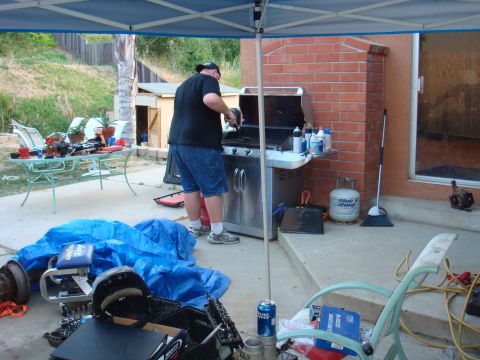 1992 Ford Bronco - Backyard scene with a man at a grill, propane tank, and various items scattered around.