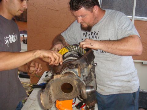 1992 Ford Bronco - Two men work on a differential assembly, a component of a vehicle's drivetrain.