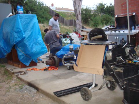 1992 Ford Bronco - A vehicle axle assembly is being worked on outdoors, with tools and other parts scattered around the scene.
