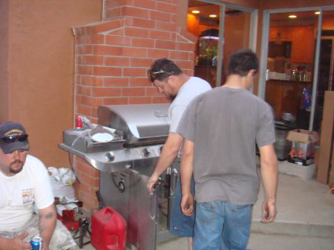 1992 Ford Bronco - Men are gathered around a gas grill on a patio, with a brick structure behind them.