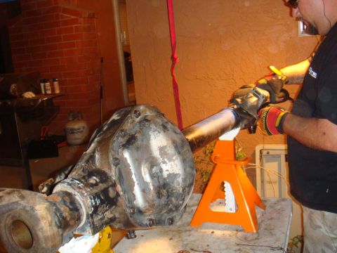 1992 Ford Bronco - A person works on a vehicle axle assembly that is supported by jack stands.