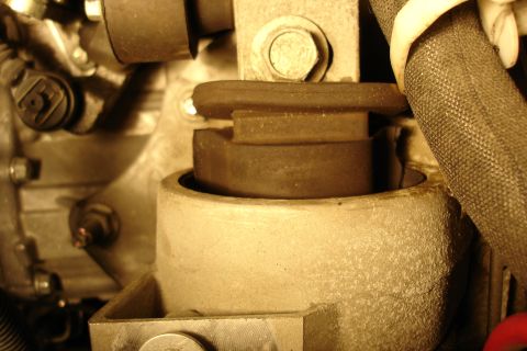 2006 Ford Fusion - Close-up of an engine or transmission mount showing a cylindrical rubber bushing seated in a metal housing, with a large hex bolt above and…