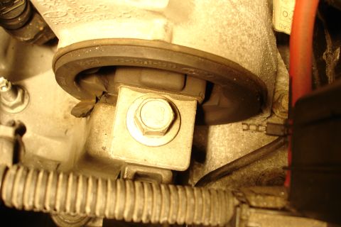2006 Ford Fusion - Close-up of a large hex bolt marked '10.9' securing a metal bracket or mount to an aluminum engine component, with a rubber-edged pulley or…