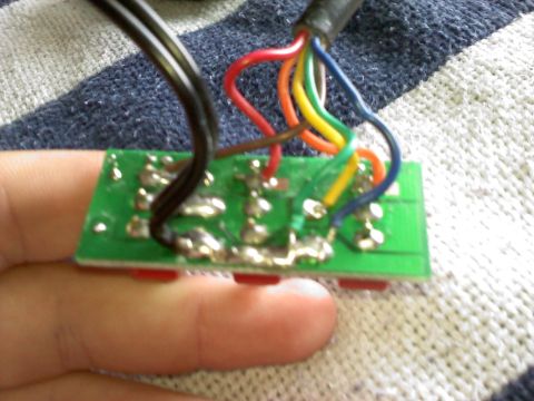 1996 Ford Bronco - A close-up view of a circuit board with various wires connected, held by a person's fingers.