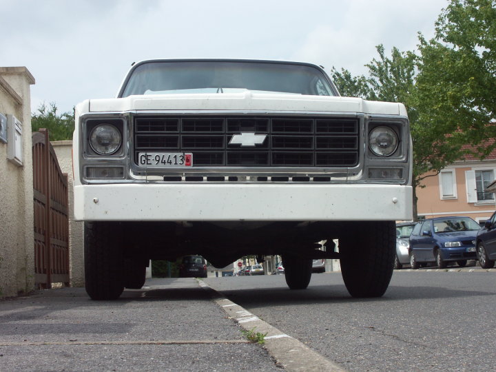 Front view of a lifted white 1970s Chevrolet pickup with bowtie grille emblem