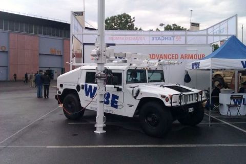 1991 Ford Crown Victoria - White Humvee modified with telescopic masts and "WIBE" branding, displayed outdoors.