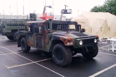 1991 Ford Crown Victoria - A military Humvee is parked next to a large trailer, with a tent visible in the background.