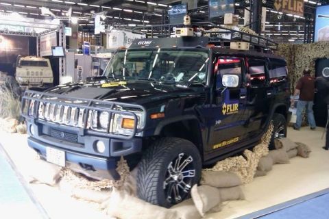 1991 Ford Crown Victoria - A black Hummer H2 is displayed indoors, possibly at an exhibition, with sandbag-like barriers around its tires.