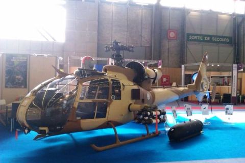 1991 Ford Crown Victoria - A military helicopter with mounted rockets and a drop tank is displayed indoors on a blue carpet.