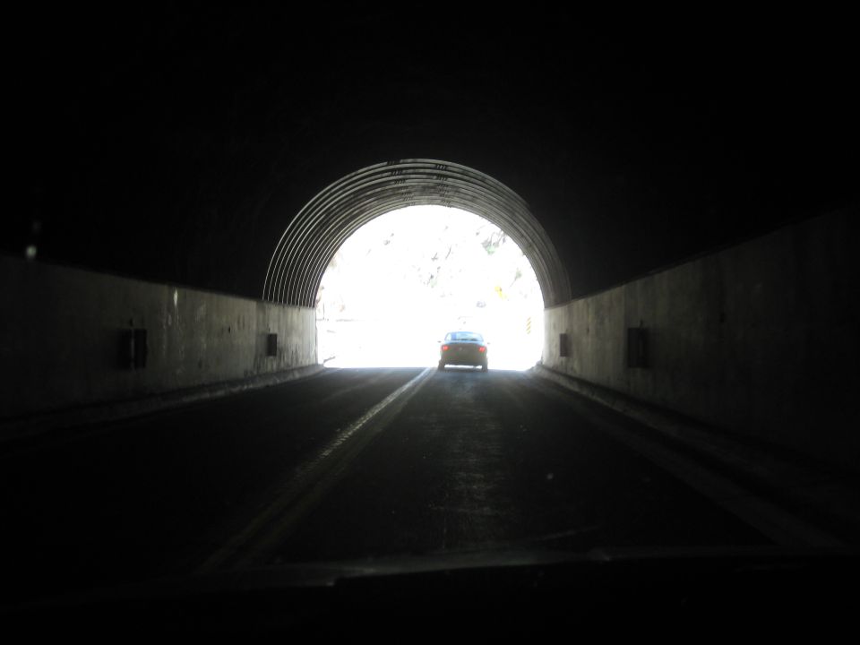 Orange car exiting a dark tunnel into bright daylight