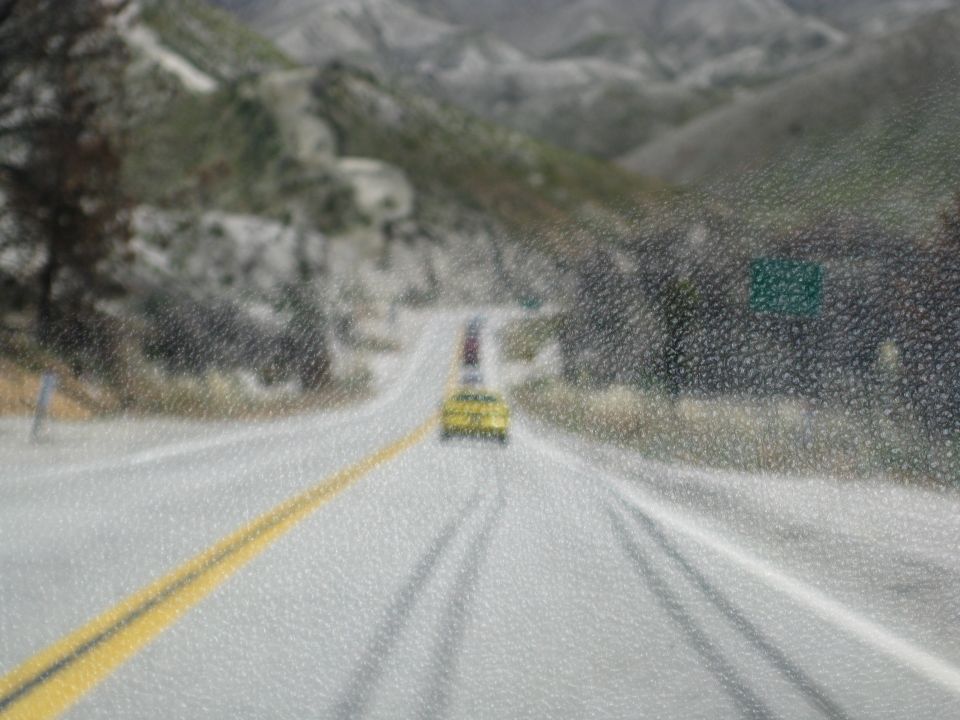 Yellow car driving on a wet road with mountains in the background
