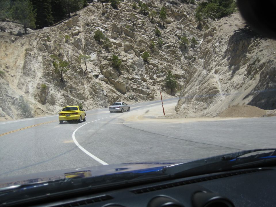Yellow sedan and silver sedan on a winding mountain road