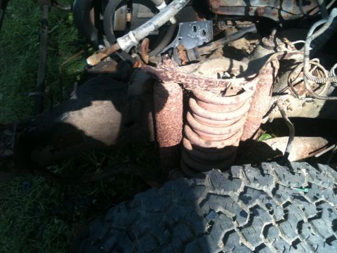 1988 Ford Bronco - This image shows a close-up view of rusty engine and suspension components, with a tire tread in the foreground.