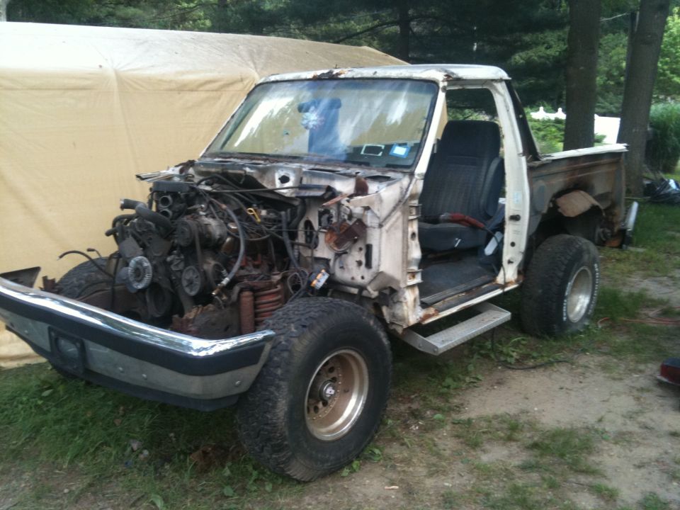 White Ford truck missing front clip and engine, showing interior and rear bed