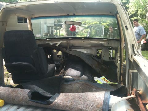 1988 Ford Bronco - The interior of a truck is shown with its dashboard removed and carpet torn, revealing its inner workings.