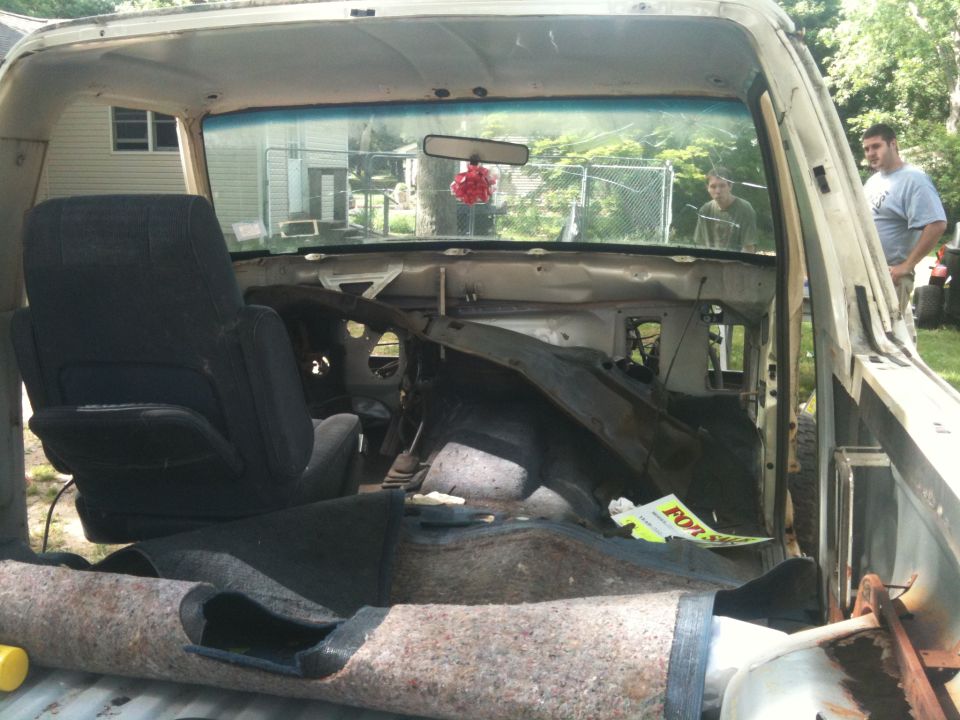 Interior of a dismantled truck with exposed dashboard and torn carpet