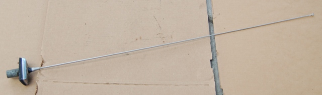 Car antenna with a black and chrome base, extended on a cardboard surface