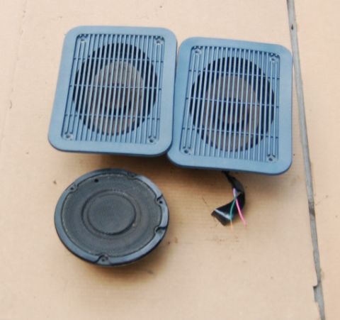 1988 Ford Bronco - Two blue-grille car speakers and one black speaker are shown on a light brown surface.