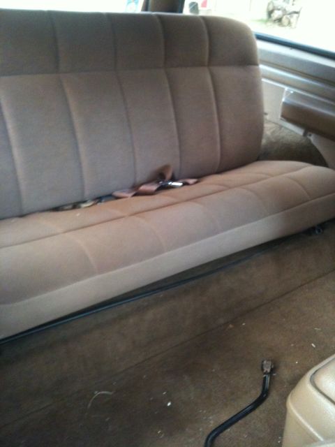 1989 Ford Bronco - Interior view of a vehicle's rear bench seat, showing the brown upholstery and seatbelt mechanism.