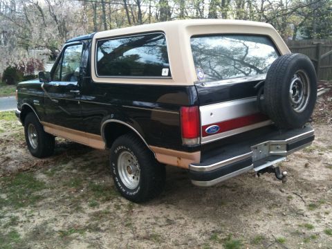 1989 Ford Bronco - This Ford Bronco is parked outdoors on a dirt and grass area, with trees in the background.