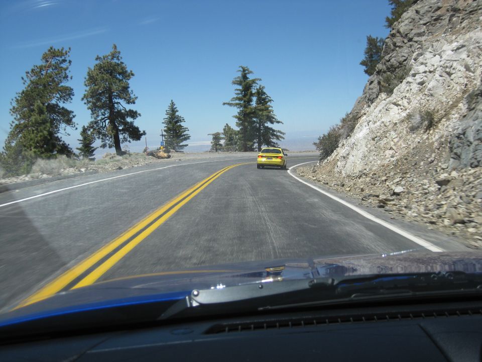 Yellow car driving on a winding mountain road, seen from another vehicle