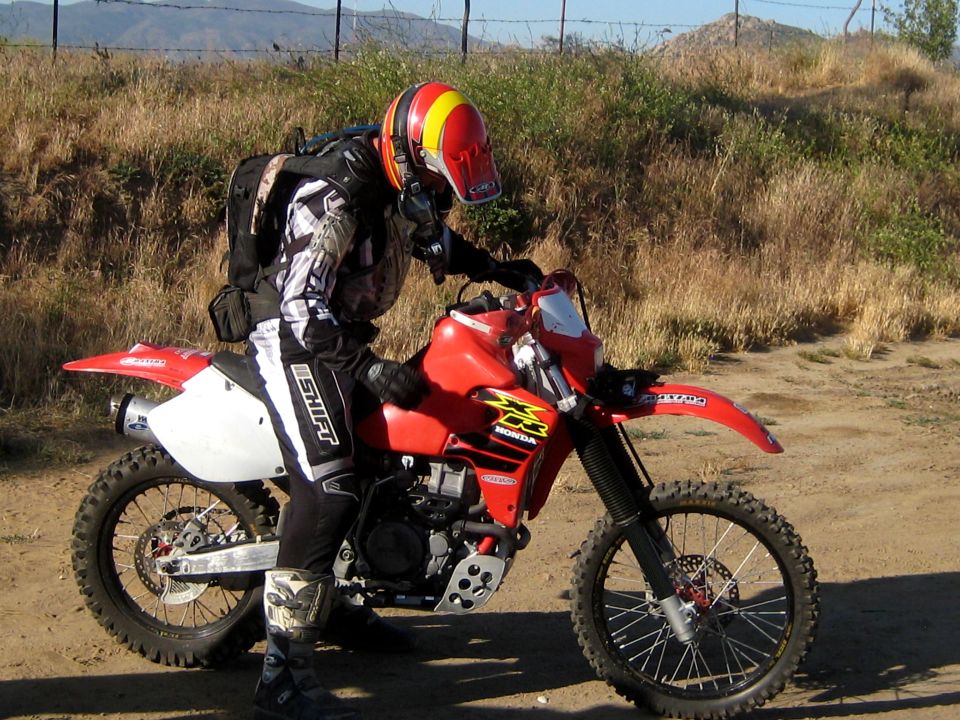 Red Honda dirt bike with rider wearing a red and yellow helmet and black and white gear