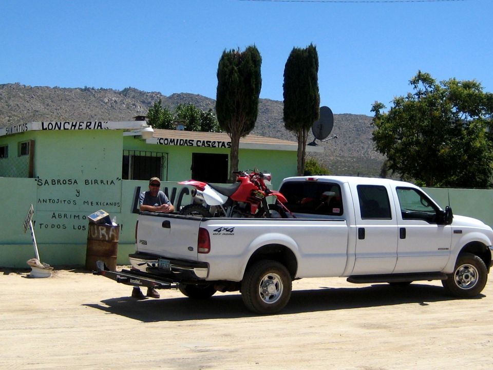 White Ford F-250 pickup truck side view, carrying a dirt bike