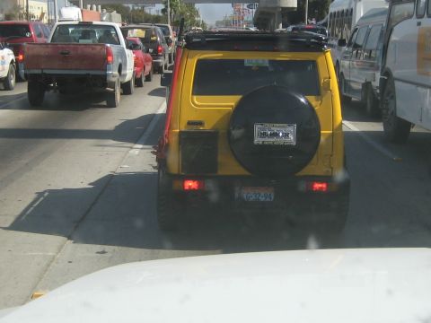 1996 Ford Bronco - Yellow SUV with spare tire on rear, license plate G-32-94, in traffic.