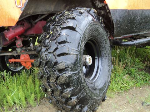 1990 Chevrolet Suburban - This photo shows a close-up of a vehicle's large, knobby tire and suspension components, covered in mud.