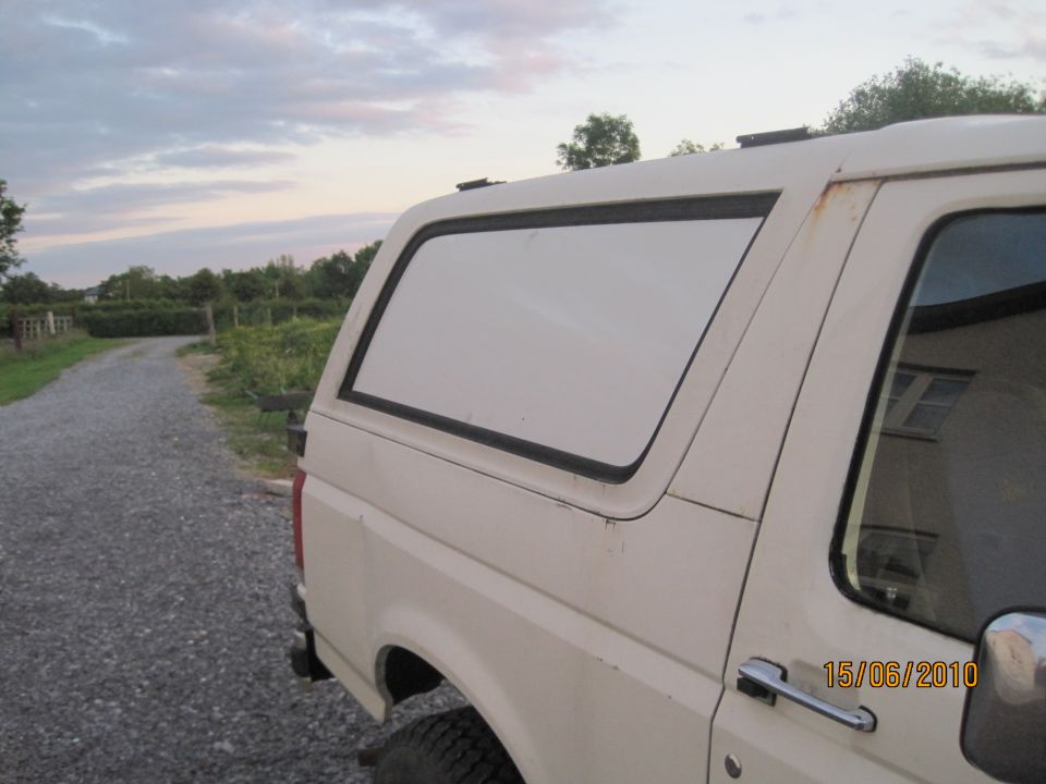 Cream Ford Bronco rear quarter view parked on gravel road at dusk