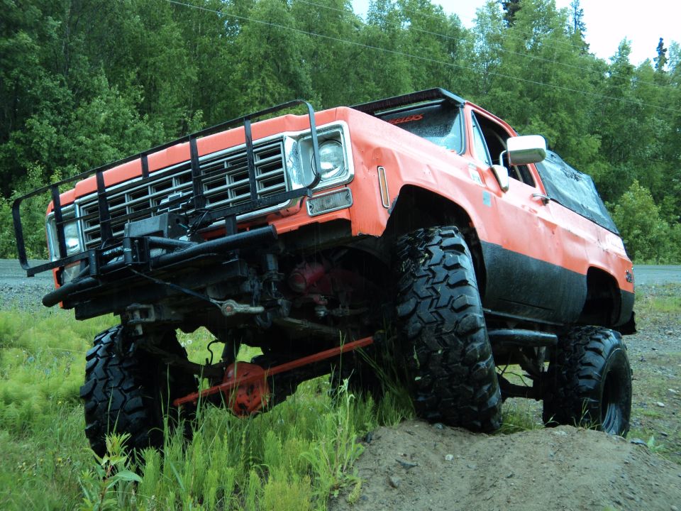 Orange lifted SUV with big tires, front bull bar, and aftermarket grille