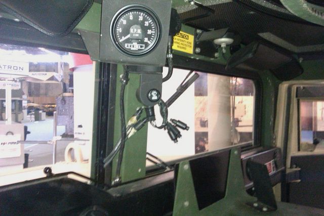 Interior shot of a vehicle showing a tachometer and dashboard. Some text is visible on a sign outside